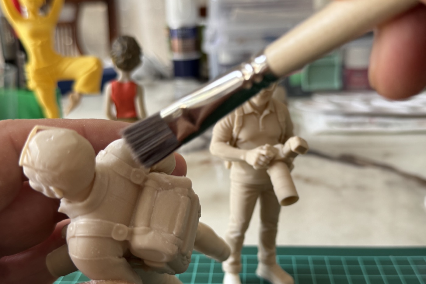 Main tenant une figurine et la nettoyant au pinceau