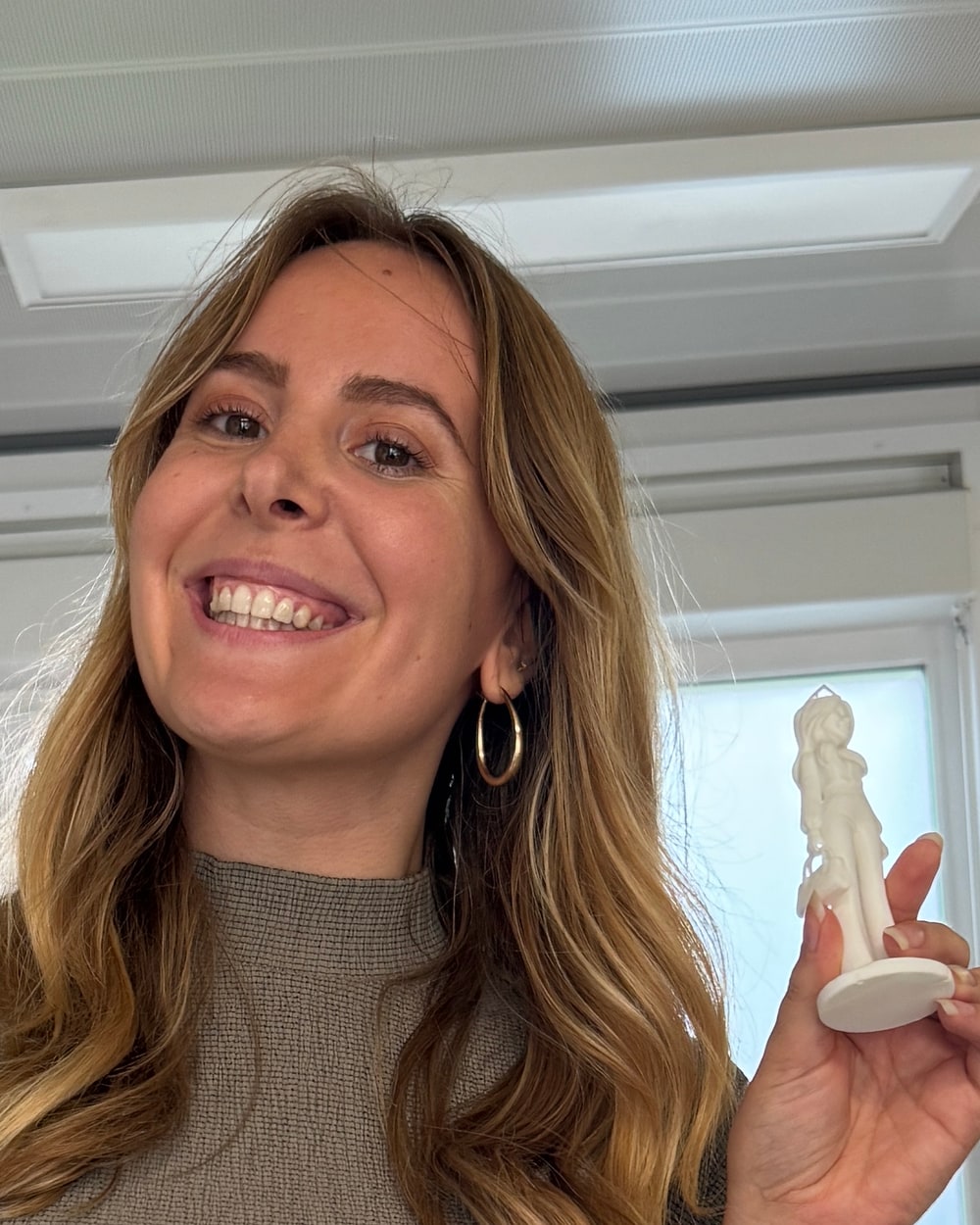 Elysa tient sa statuette en résine blanche à hauteur de visage