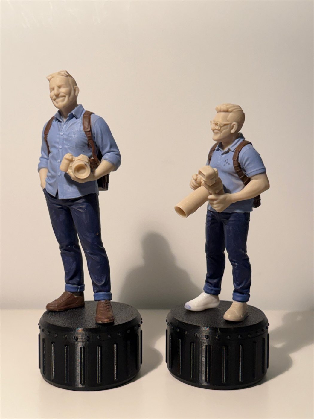 Deux figurines de photographes peintes à la main, chemise bleue, jean et sac à dos