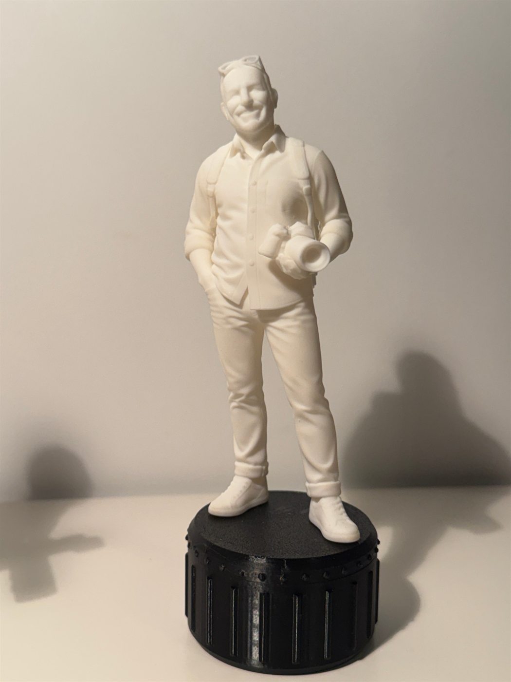 Figurine d'un homme souriant, main dans la poche, appareil photo à la main