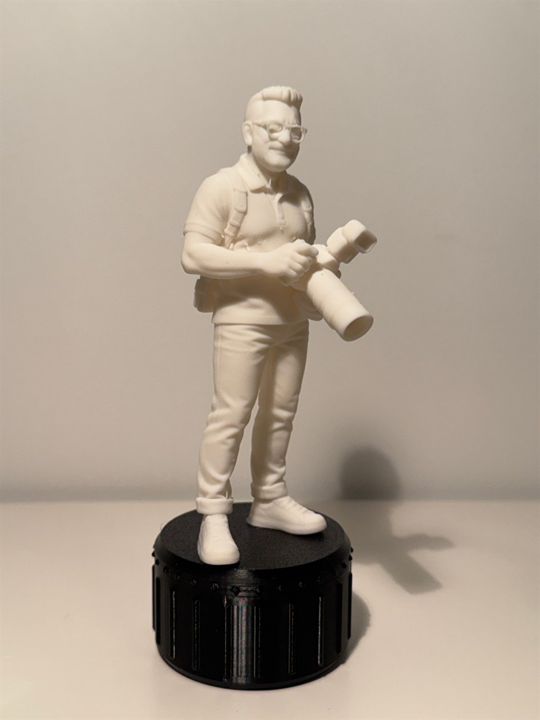 Figurine en résine blanche d'un photographe tenant un appareil à téléobjectif